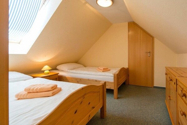 Quarto pequeno e aconchegante com duas camas de madeira, um guarda-roupa de madeira e um claraboia.