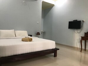 Un dormitorio con una cama, un televisor montado en la pared y una mesita.