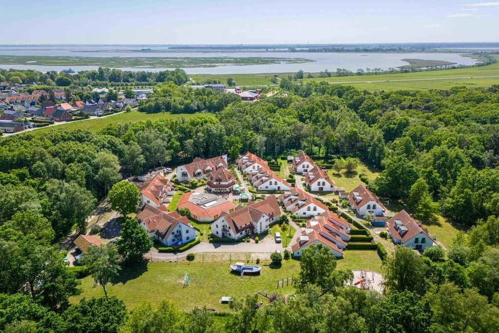 A residential area with houses, a central building with a dome, and a body of water in the background.