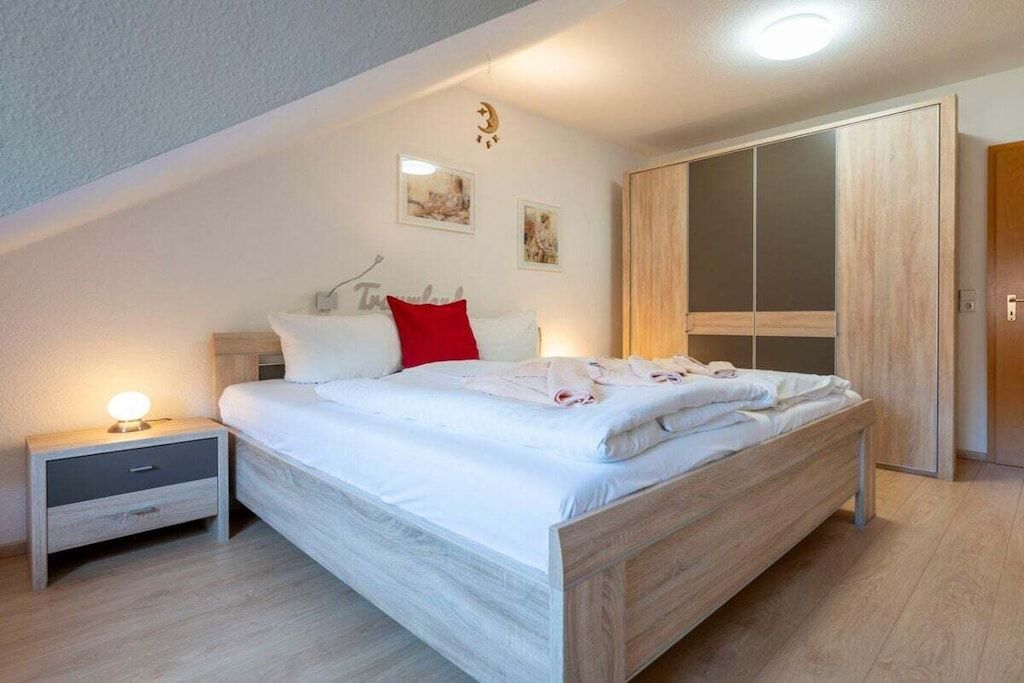 Un dormitorio con cama, mesita de noche, armario y adornos en la pared.