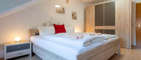 Un dormitorio con cama, mesita de noche, armario y adornos en la pared.