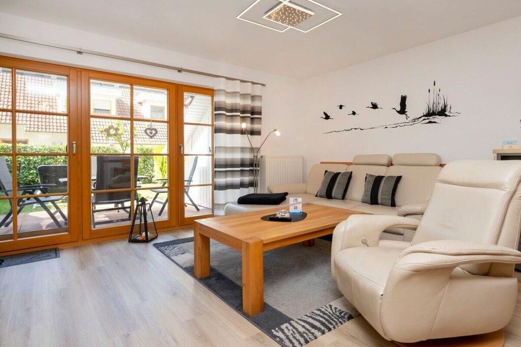 A modern living room with a sofa, a coffee table, and a view through large glass doors to an outdoor area.