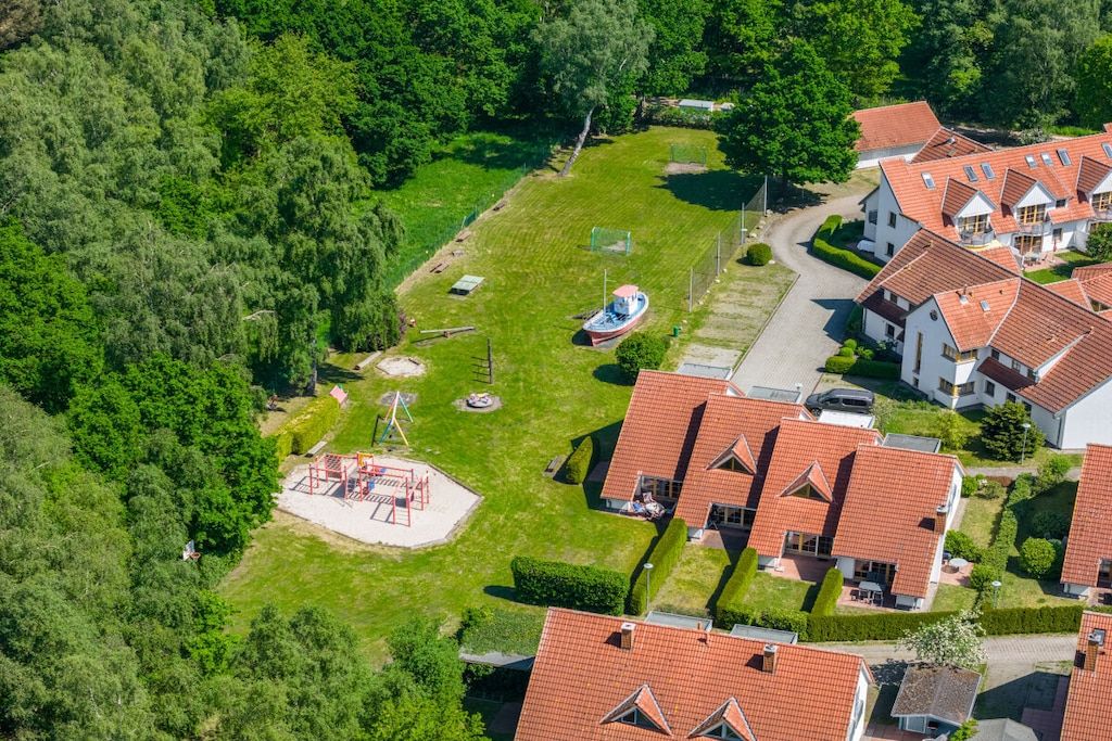 Un quartier résidentiel avec des maisons, une aire de jeux et un bateau.