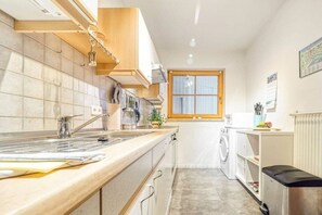 A compact kitchen with a sink, stove, and cabinets, a window, and a washing machine. - 7a/T5 in the holiday apartment park "Freesenbruch" (Zingst (Ostseeheilbad))