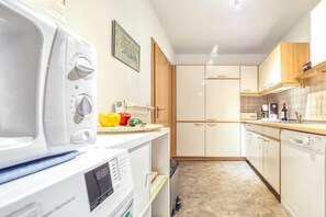 A compact kitchen with white appliances, wooden cabinets, and a tiled backsplash. - 7a/T5 in the holiday apartment park "Freesenbruch" (Zingst (Ostseeheilbad))