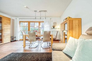 A modern living room with a sofa, a dining table with chairs, and a kitchen area with cabinets. - 7a/T5 in the holiday apartment park "Freesenbruch" (Zingst (Ostseeheilbad))