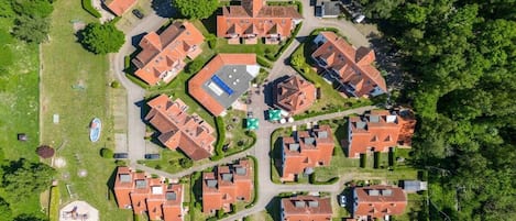 Vista aérea de um bairro residencial com várias casas, uma piscina e gramados bem cuidados.