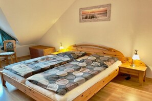Una camera da letto con un letto a soppalco, una sedia, un comodino con una lampada e un quadro appeso al muro.