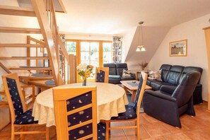 A dining area with a round table, chairs, and a staircase. - 3.5/T3 holiday home park “Freesenbruch” (Zingst (Ostseeheilbad))