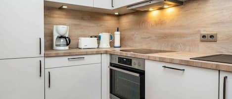 A modern kitchen with white cabinets, a built-in oven, a coffee maker, and a toaster.