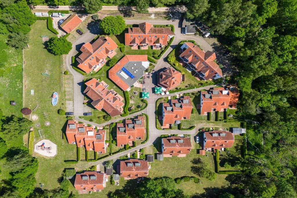 Vista aérea de uma área residencial com várias casas, ruas e áreas verdes.