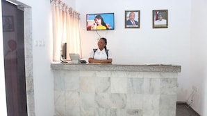 Un comptoir d’accueil avec un écran de télévision, un portrait encadré et un téléphone.