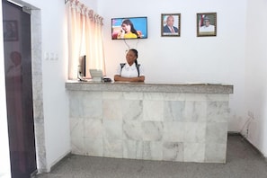 A reception desk with a television screen, a framed portrait, and a telephone. - Phisbond Hotels (Uyo)