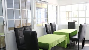 Un espace repas avec des tables et des chaises, de grandes fenêtres et une vue sur l’extérieur.