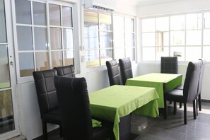 A dining area with tables and chairs, large windows, and a view of the outside. - Phisbond Hotels (Uyo)