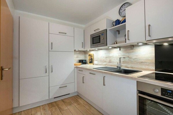 Eine moderne Küche mit weißen Schränken, einer Mikrowelle, einem Spülbecken und einem Backofen.