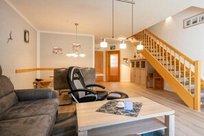 Uma sala de estar moderna com um sofá, uma poltrona, uma mesa e uma escada.