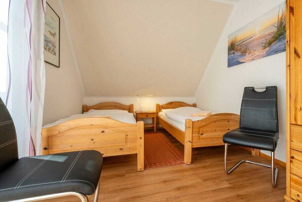 Une petite pièce chaleureuse, avec deux lits en bois, une seule chaise et un tableau accroché au mur.