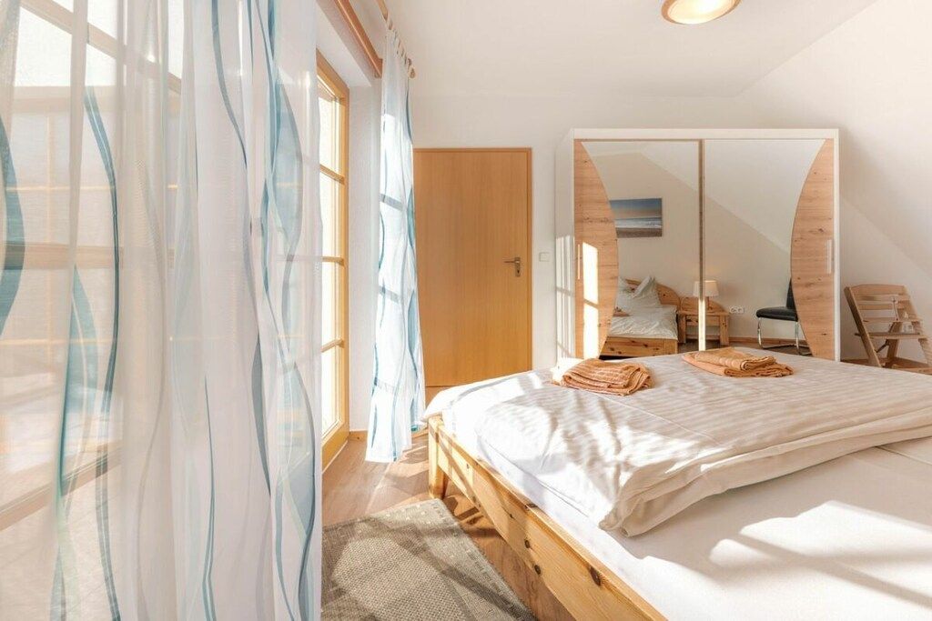 A bedroom with a wooden bed, a large mirror, and a view of the outside.