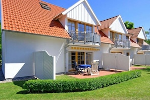 Een rij witte gebouwen met rode pannendaken en balkons.