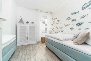 Een kamer met een bed, een witte inbouwkast, een blauwe bank en een muur met visstickers.