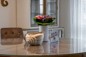 A glass-top table with a white vase containing flowers, a woven basket, and a QR code sign. - Park Residence Am Hafen 23 - “Viento” (Seeheilbad Zingst)