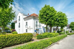 Un bâtiment blanc avec une enseigne indiquant « Parkresidenz » et un grand arbre devant.