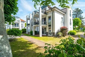 Ein mehrstöckiges Wohngebäude mit Balkonen, einem gepflegten Rasen und blauem Himmel.