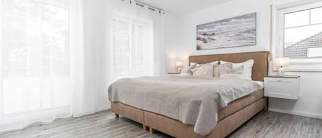 A bedroom with a bed, bedside tables, a window, and a painting on the wall.