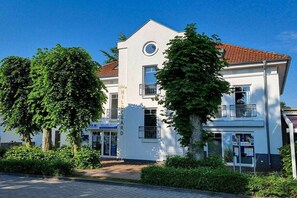 A two-story building with a white facade, a red-tiled roof, and a circular window on the upper floor. - Park Residence Am Hafen 23 - “Viento” (Seeheilbad Zingst)
