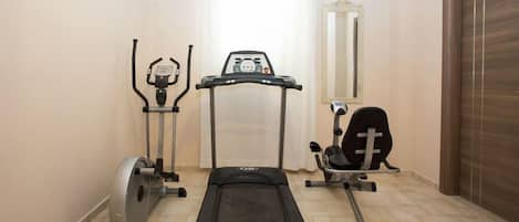 A home gym with a treadmill, elliptical, and stationary bike.
