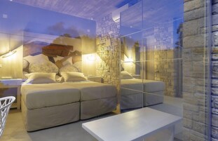 Un dormitorio moderno con cama, mesitas de noche y un separador de vidrio.