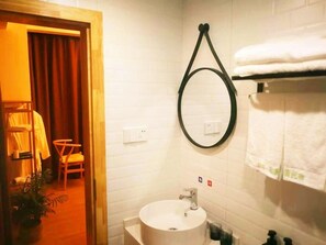 Un baño con espejo redondo, lavamanos blanco y barra para toallas.