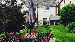 Une terrasse avec une table et des chaises, une plante en pot et un bâtiment en arrière-plan.