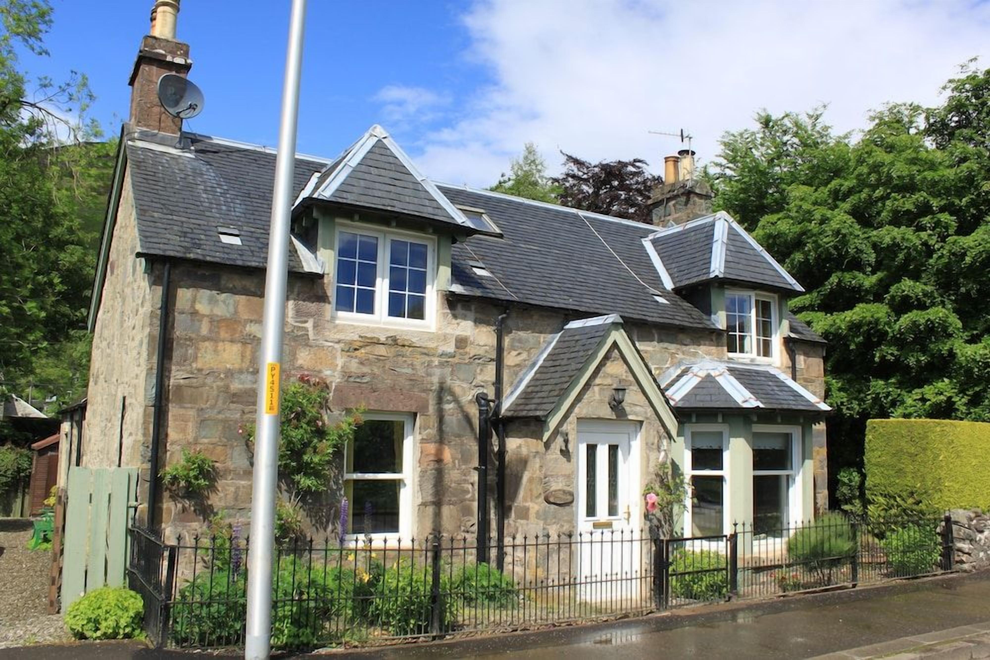 A stone house with multiple windows and a chimney.