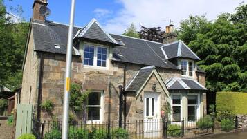 A stone house with multiple windows and a chimney.