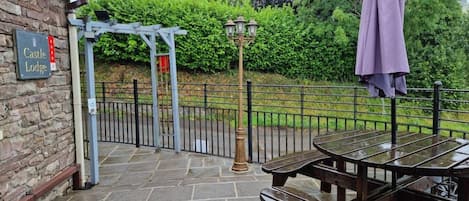 A stone patio with picnic tables and a sign for Castle Lodge.