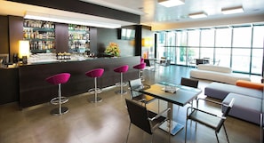 Un área de bar moderna con una barra, taburetes y un espacio de estar con un sofá y sillas.