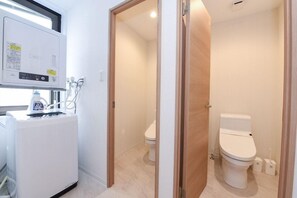 A compact bathroom with a toilet, a small sink, and a heater unit. - Ryo-an (Otaru)