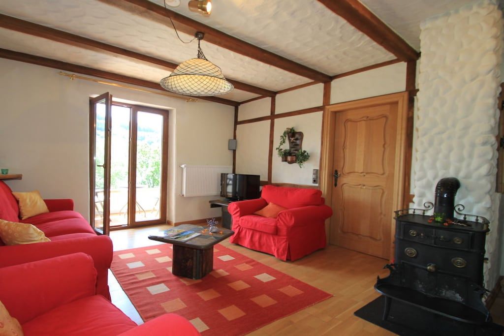 A living room with a red sofa, a wooden coffee table, and a black stove.