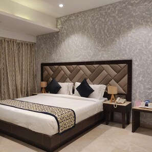 Habitación de hotel moderna con una cama grande, cabecera con diseño de rombos, dos mesitas de noche con lámparas y una pared con textura.