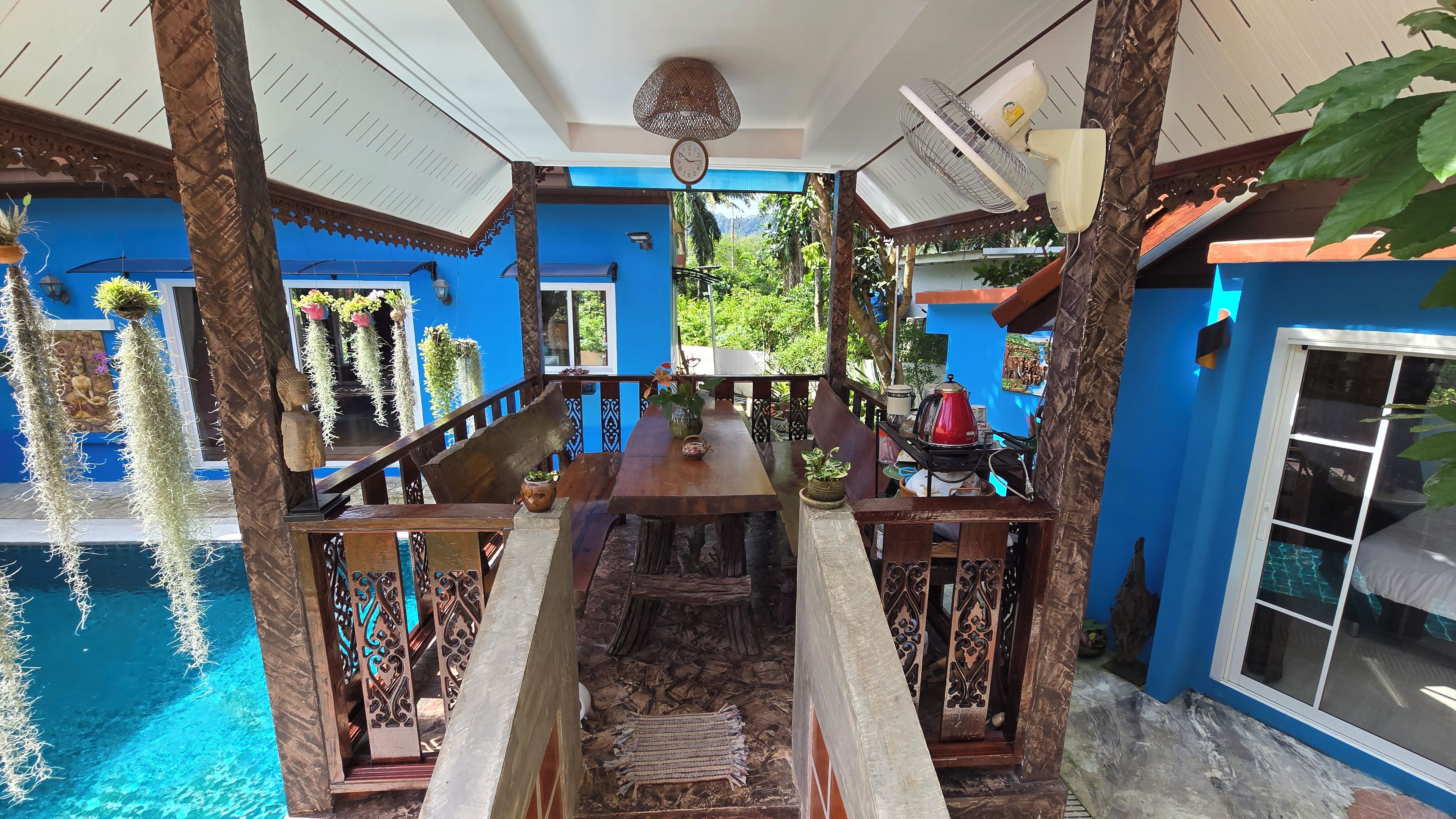 Une pièce avec une piscine, une table en bois et un mur bleu.