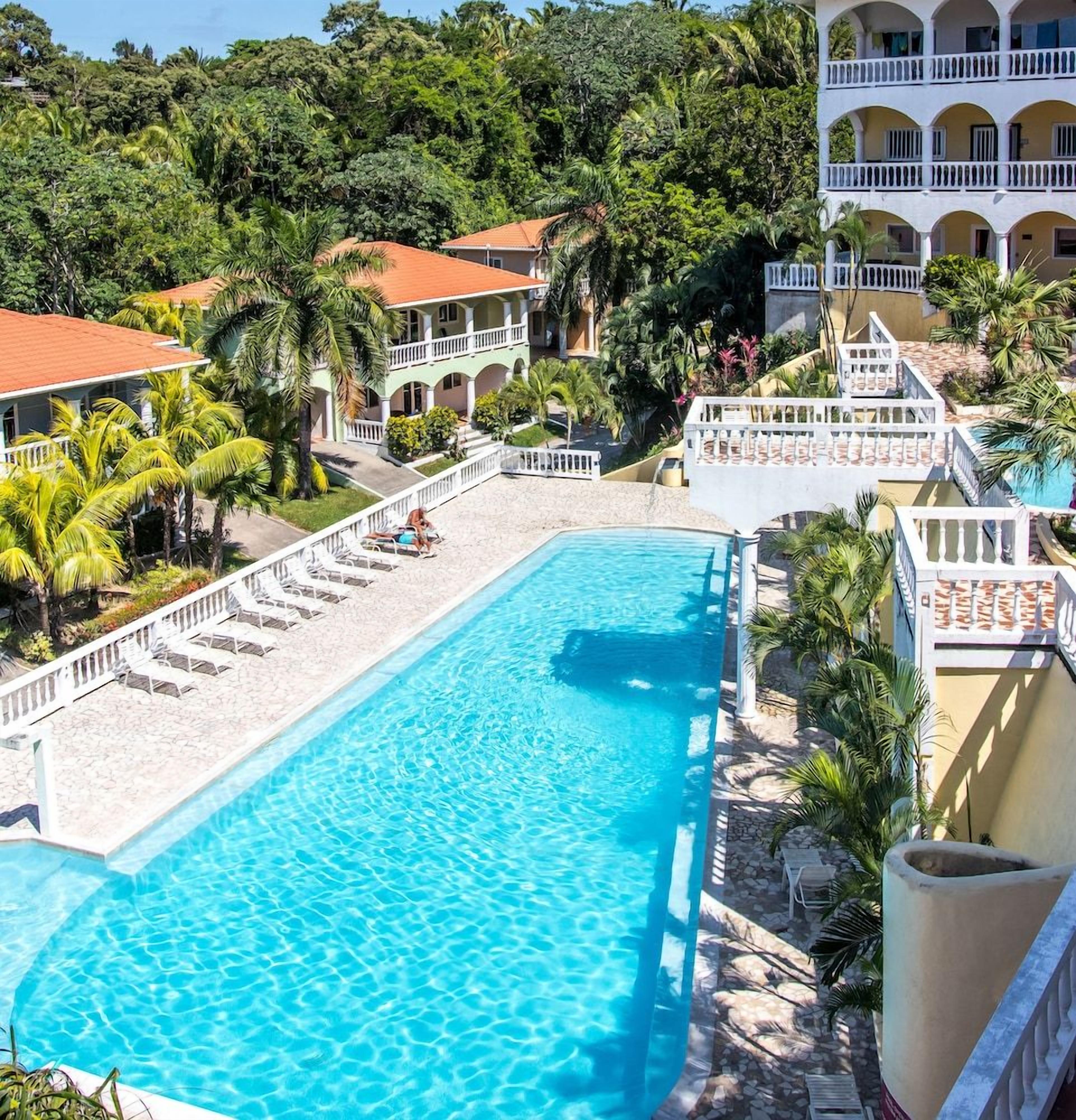 Un complexe hôtelier doté d’une piscine, de nombreux balcons et d’une végétation luxuriante.