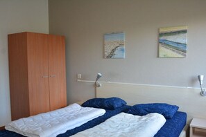 A bedroom with a bed, a wardrobe, and two wall-mounted lamps. - Holiday home with 1 bedroom (Julianadorp)