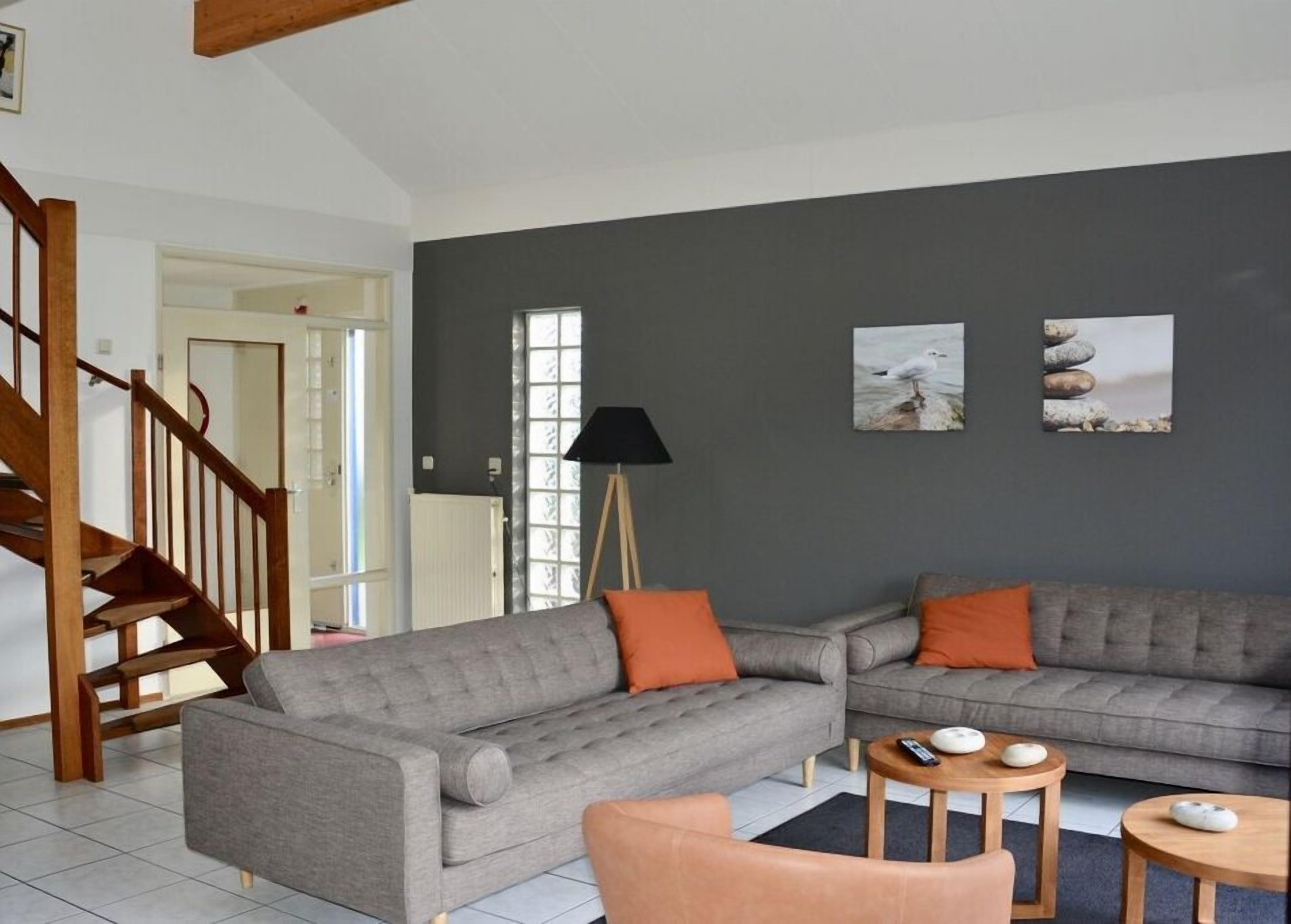 A living room with a grey sofa set, a wooden coffee table, and a lamp.