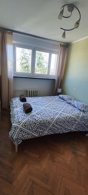 A room with a bed, a radiator, a window, and a ceiling light fixture.