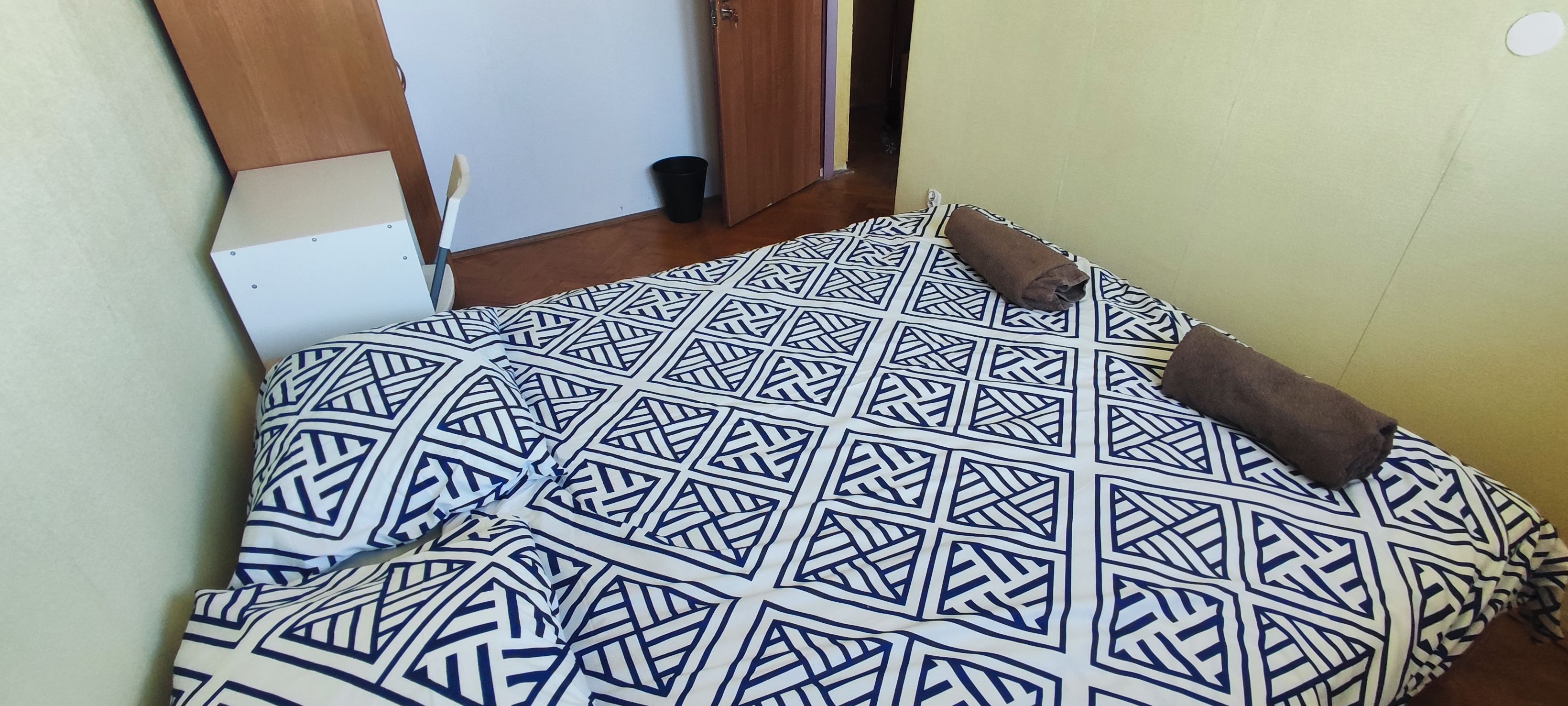 A bed with a patterned bedspread and a brown pillow.