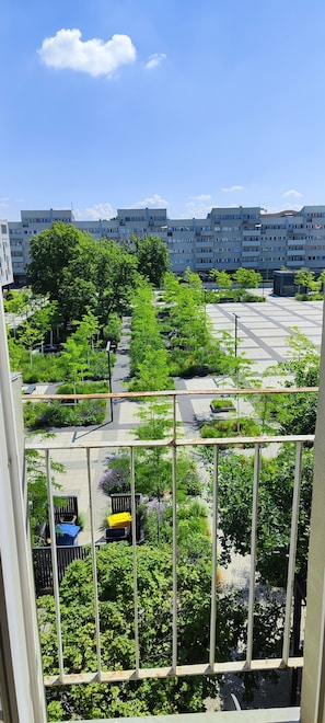 A balcony with a view of a green park and residential buildings.