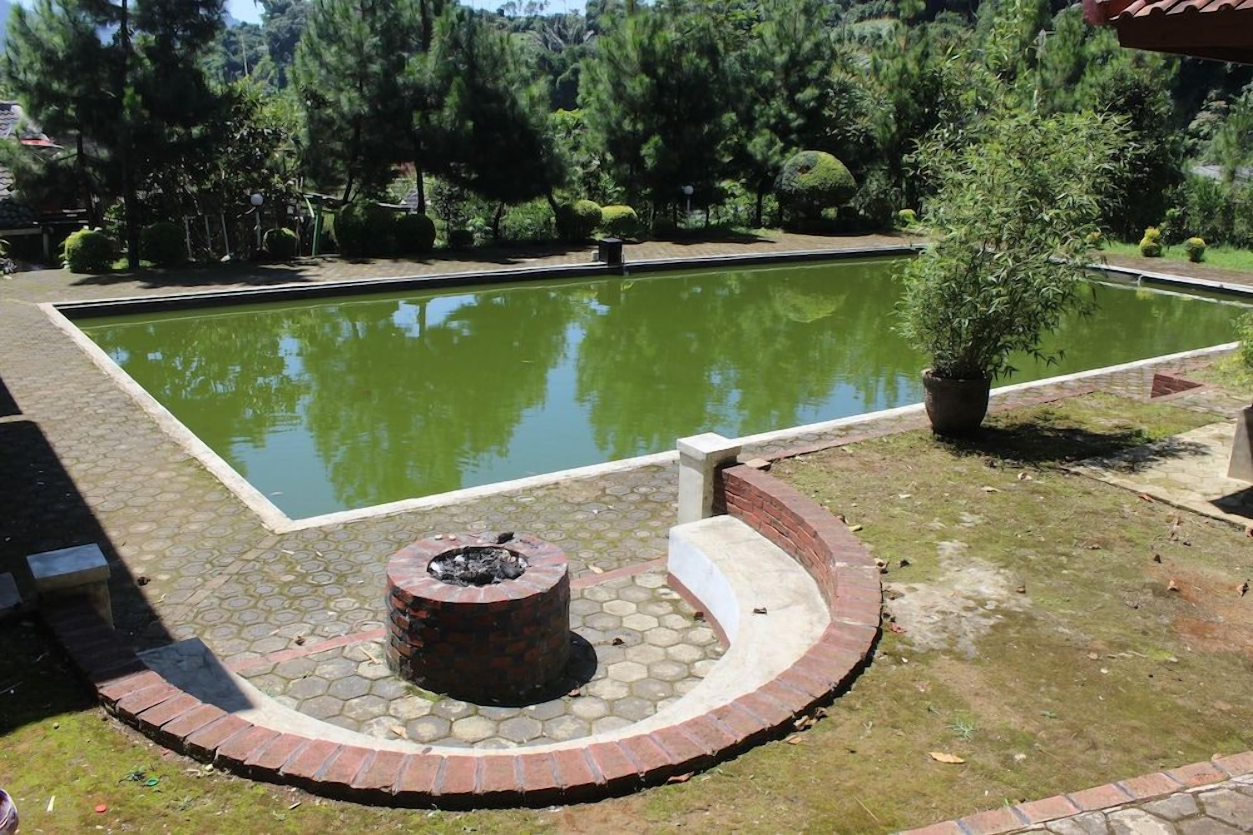 A rectangular pool with a brick fire pit in the center, surrounded by a brick border.