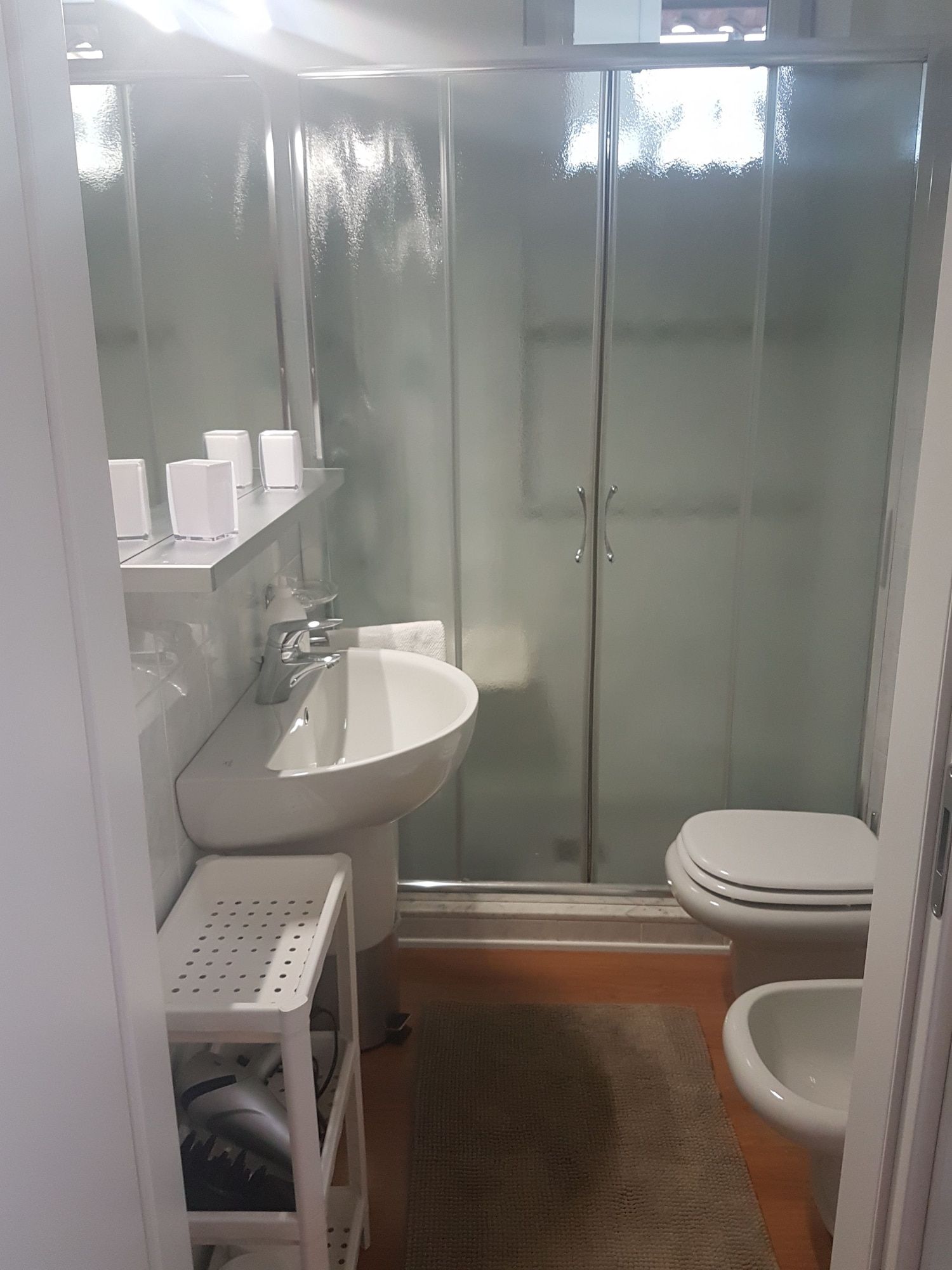 Un bagno con lavandino bianco, WC e cabina doccia in vetro.
